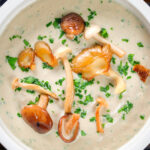 Overhead close-up creamy wild mushroom soup garnished with fried mushrooms.