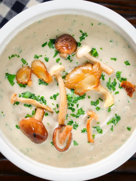 Overhead close-up creamy wild mushroom soup garnished with fried mushrooms.