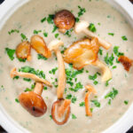Overhead close-up creamy wild mushroom soup garnished with fried mushrooms.
