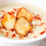 Close up Creamy Jerusalem artichoke soup garnished with paprika and fried sunchoke crisps.