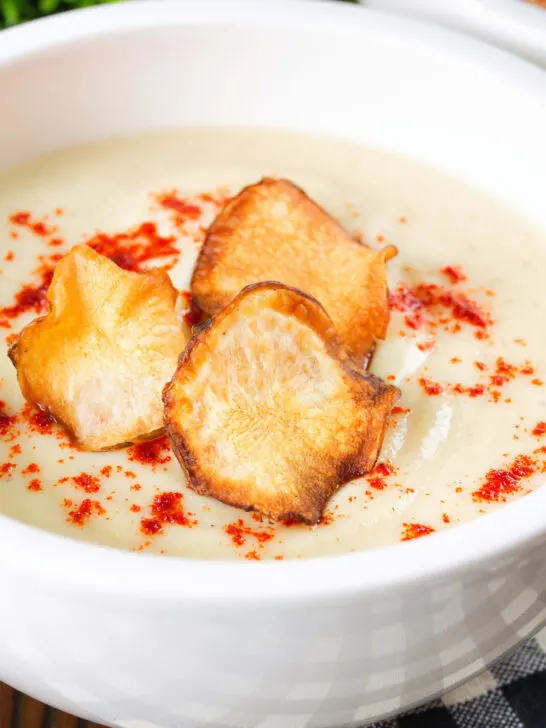 Close up Creamy Jerusalem artichoke soup garnished with paprika and fried sunchoke crisps.