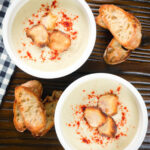Overhead creamy Jerusalem artichoke soup garnished with paprika and fried sunchoke crisps.