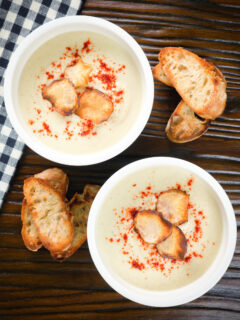 Overhead creamy Jerusalem artichoke soup garnished with paprika and fried sunchoke crisps.