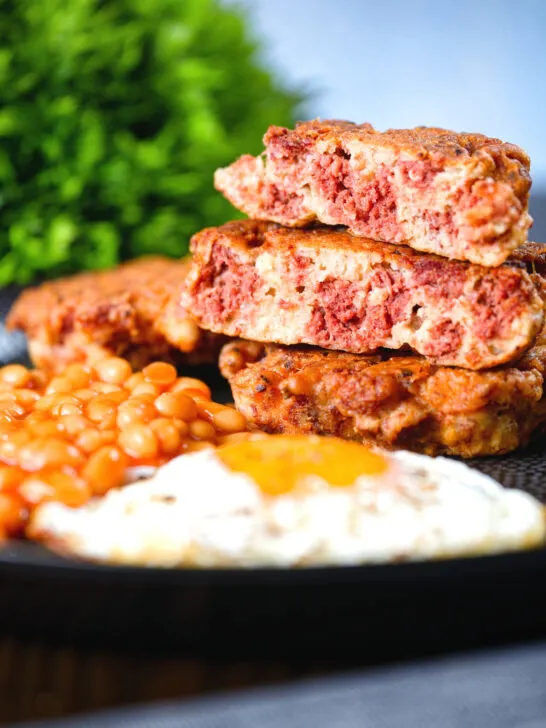 Crispy corned beef fritters cut open to show texture served with fried egg and beans.