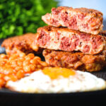 Crispy corned beef fritters cut open to show texture served with fried egg and beans.