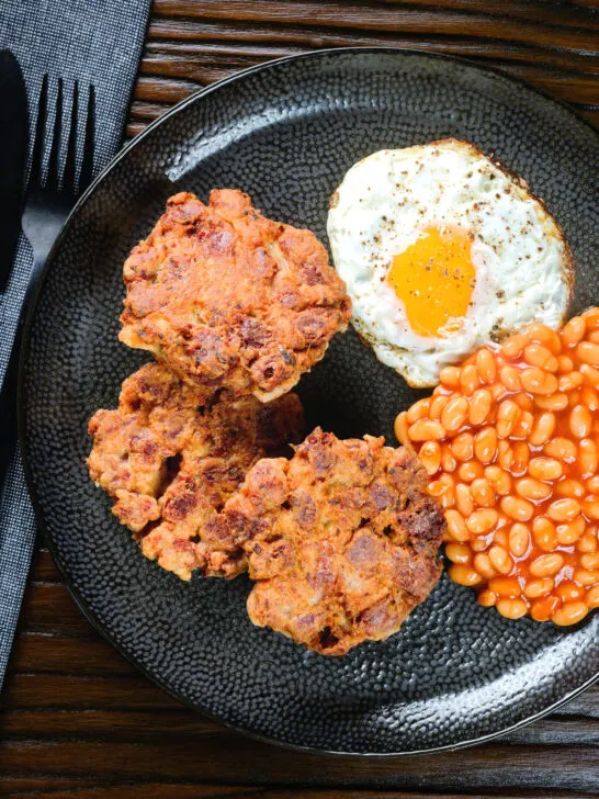 Overhead crispy canned corned beef fritters with fried egg and beans.