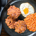 Overhead crispy canned corned beef fritters with fried egg and beans.