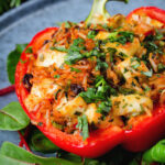 Close-up baked stuffed peppers with halloumi cheese, brown rice, harissa pasta and raisins.