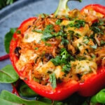 Close-up baked stuffed peppers with halloumi cheese, brown rice, harissa pasta and raisins.