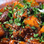 Close-up Indian potato and oxtail curry served with rice.