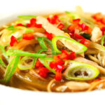 Close-up Chinese influenced spicy leftover roast chicken soup with noodles.