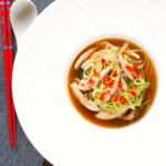 Overhead Chinese influenced spicy leftover roast chicken soup with noodles.