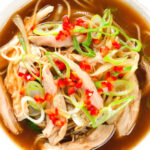Close-up overhead Chinese influenced spicy leftover roast chicken soup with noodles.