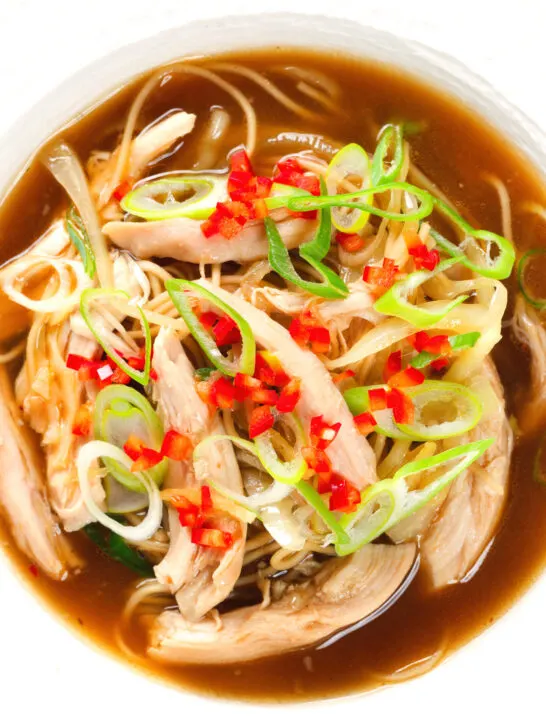 Close-up overhead Chinese influenced spicy leftover roast chicken soup with noodles.