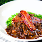 Braised liver and onions, in a rich onion gravy served with crispy bacon and peas.