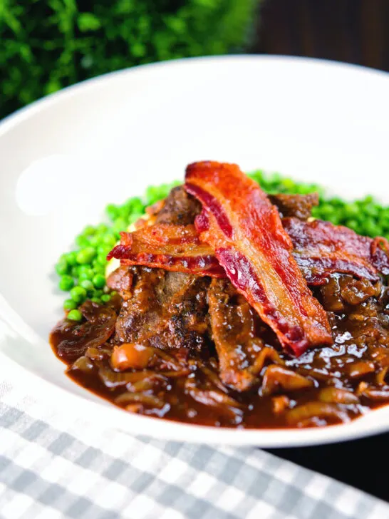 Braised liver and onions, in a rich onion gravy served with crispy bacon and peas.