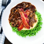 Overhead liver and onions, in onion gravy served with crispy bacon, mashed potato and peas.
