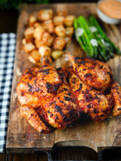 Whole baked peri peri spatchcock chicken served with Parmentier potatoes and garlic asparagus.