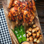 Overhead whole baked peri peri spatchcock chicken served with Parmentier potatoes and garlic asparagus.
