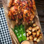 Overhead whole baked peri peri spatchcock chicken served with Parmentier potatoes and garlic asparagus.