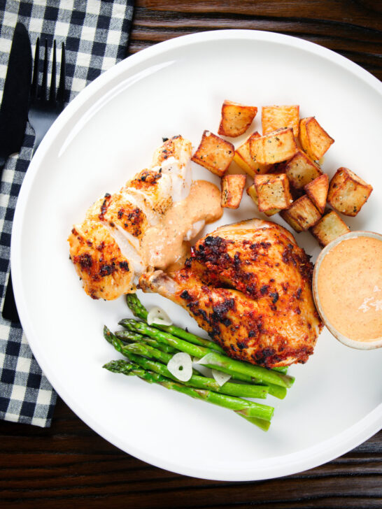 Overhead peri peri spatchcock chicken served with roasted potatoes, asparagus and garlic mayo.