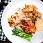 Overhead peri peri spatchcock chicken served with roasted potatoes, asparagus and garlic mayo.