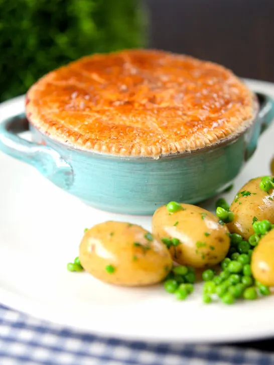 Pork and apple pie with a puff pastry lid served with buttered new potatoes and peas.