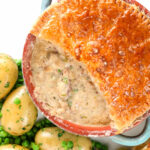 Overhead close-up pork and apple pie with a puff pastry lid (partially removed).