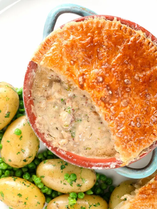 Overhead close-up pork and apple pie with a puff pastry lid (partially removed).