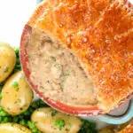 Overhead close-up pork and apple pie with a puff pastry lid (partially removed).