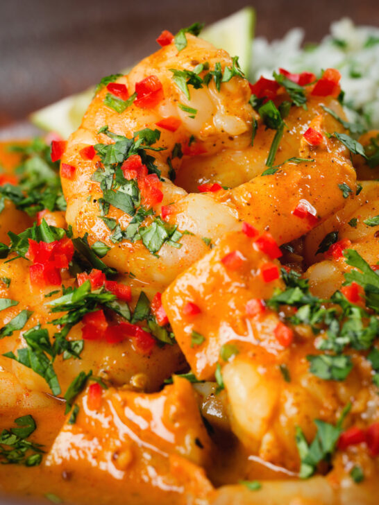 Close-up prawn and mango curry in a coconut milk sauce served with herby rice.