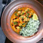 Overhead Indian-influenced prawn and mango curry in a coconut milk sauce served with herby rice.