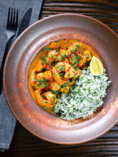 Overhead Indian-influenced prawn and mango curry in a coconut milk sauce served with herby rice.