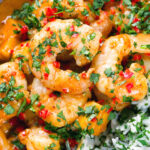 Close-up overhead prawn and mango curry in a coconut milk sauce served with herby rice.