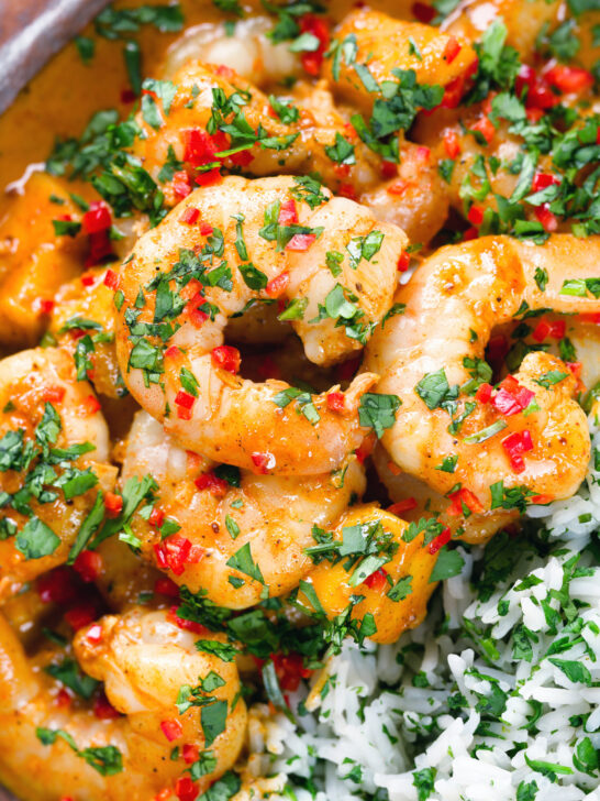 Close-up overhead prawn and mango curry in a coconut milk sauce served with herby rice.