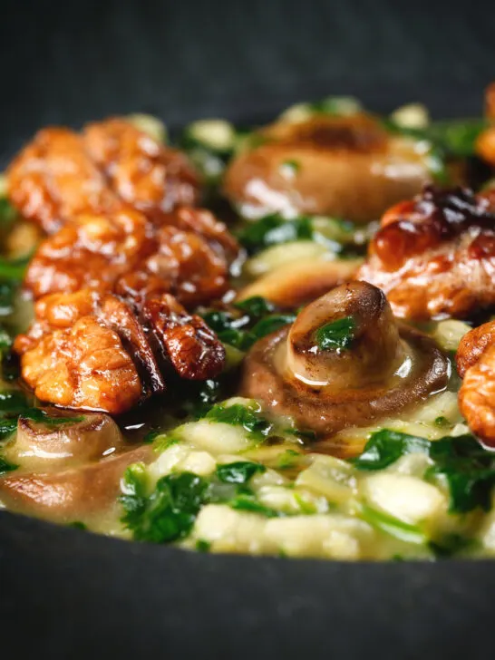 Close-up mushroom and spinach risotto topped with brown butter cooked walnuts.