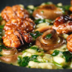 Close-up mushroom and spinach risotto topped with brown butter cooked walnuts.