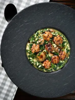 Overhead mushroom and spinach risotto topped with brown butter cooked walnuts.