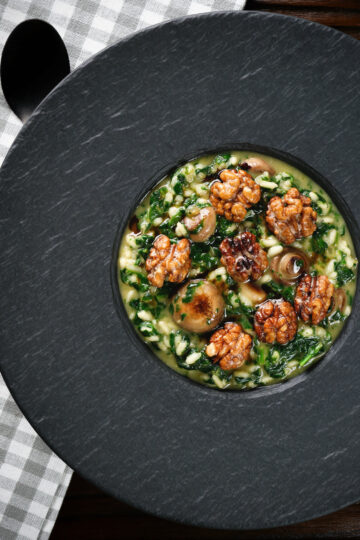 Overhead mushroom and spinach risotto topped with brown butter cooked walnuts.