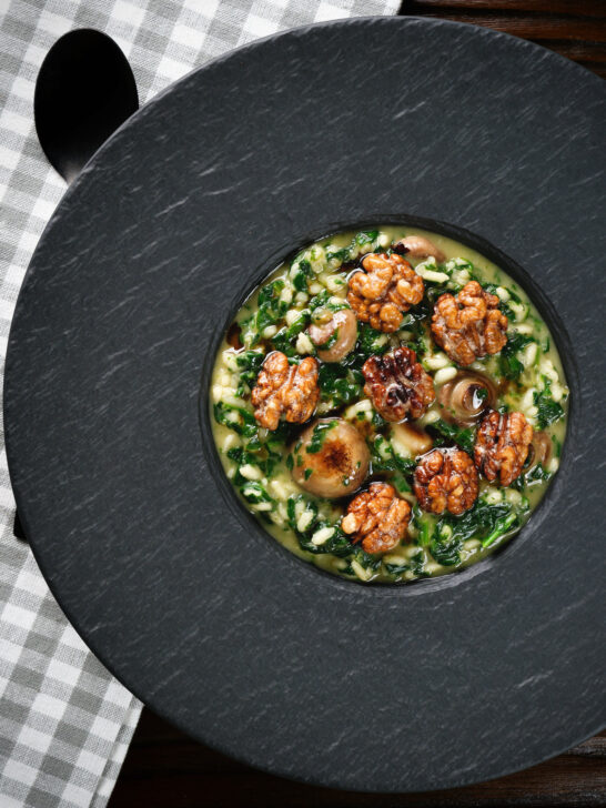 Overhead mushroom and spinach risotto topped with brown butter cooked walnuts.