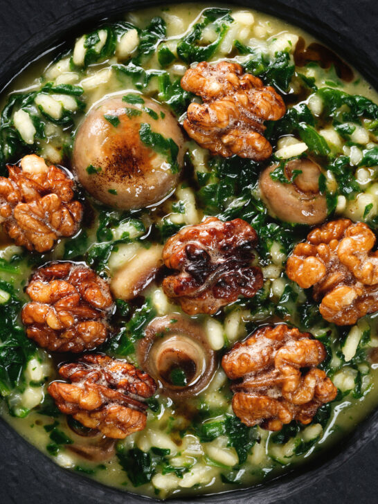 Close-up overhead mushroom and spinach risotto topped with brown butter cooked walnuts.