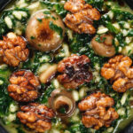 Close-up overhead mushroom and spinach risotto topped with brown butter cooked walnuts.