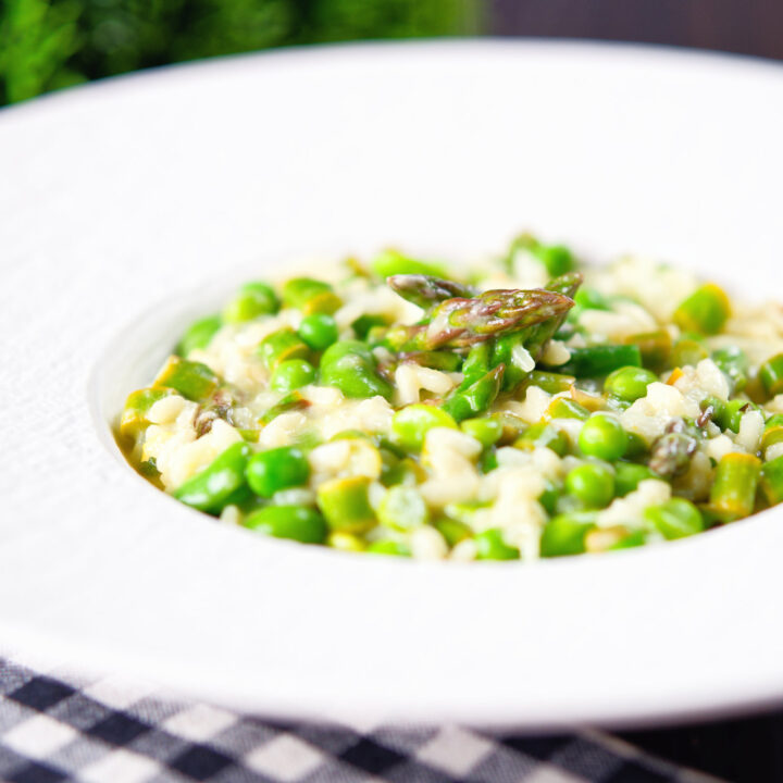 Lemon, pea, broad bean and asparagus risotto served in a white bowl.