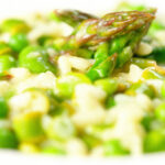 Close-up creamy spring broad bean, pea and asparagus risotto.