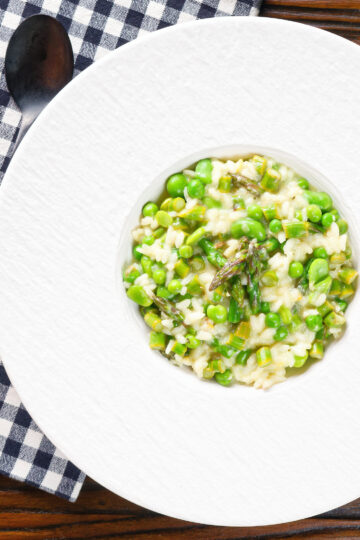 Overhead creamy spring broad bean, pea and asparagus risotto.