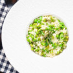 Overhead creamy spring broad bean, pea and asparagus risotto.