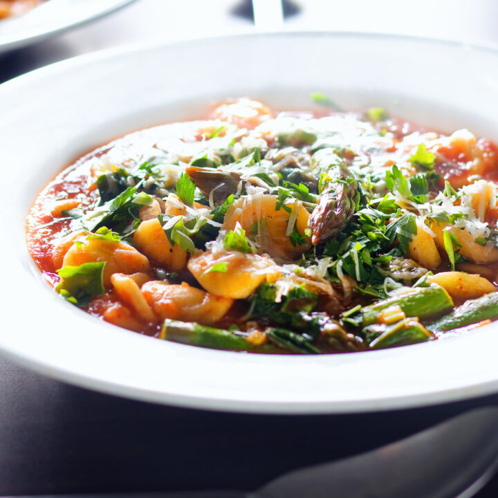 One-pot asparagus and Tomato Orecchiette Pasta with Wild Garlic garnished with parmesan.