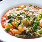 Asparagus and tomato orecchiette pasta soup/stew with wild garlic.