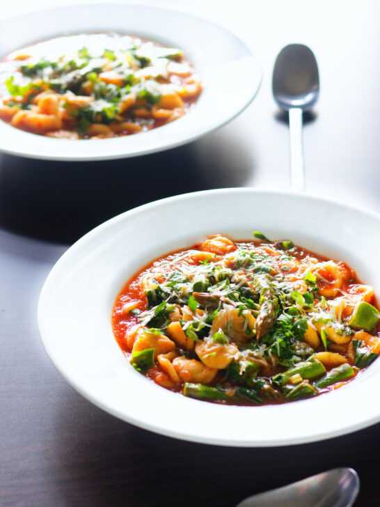 Two bowls of asparagus and tomato orecchiette pasta soup/stew with wild garlic.