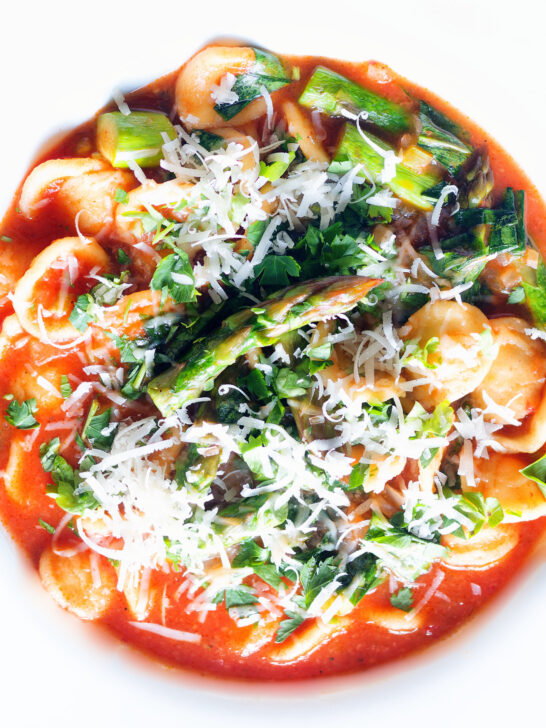 Overhead close-up asparagus and tomato orecchiette pasta soup/stew with wild garlic.